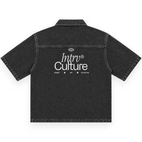 Front view of INTROVERT "Culture" heavy-weight washed black denim short sleeve button-down shirt with contrast stitching, silver hardware snap buttons, and white script branding on the chest pocket.